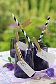Place cards clipped to purple glasses with gold clothes pegs and drinking straws with washi-tape flags