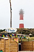 A beach bar in front of a lighthouse in the fog, Hörnum