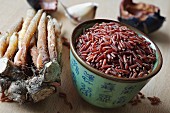An arrangement of fingerroot and a bowl of red rice (Thailand)