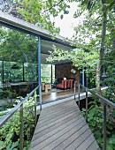 Wooden boardwalk with direct access to interior of concrete house through sliding glass wall