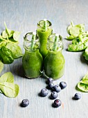 Three bottles of green smoothies with ingredients