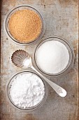 Various types of sugar in glass bowls: white sugar, brown sugar and icing sugar