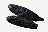 Two tonka beans on a white surface