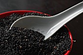 Roasted black sesame seeds with a porcelain spoon in a bowl