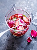 Ein Glas Erdbeerbowle mit Rosenblättern