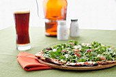 Pizza with rocket and cheese served with beer and salt and pepper