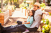 Portrait of girl sitting on fathers knee in garden