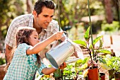 Girl and father watering plants in garden