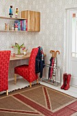 Desk, chairs with red upholstery, wall-mounted shelf and wallpaper with pale pattern