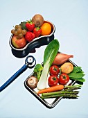 Obst in Nierenschale, Gemüse auf Metalltablett & dazwischen Stethoskop