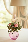 Arrangement of roses and table number in spherical glass vase