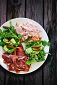 A plate of ham with lettuce and gherkins