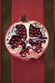 Half a pomegranate on a red wooden slat (seen from above)