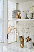 Plates, cups and glasses with gilt ornamentation in dresser