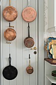 Copper pans hung on white-painted wooden door