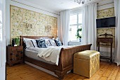 Traditionelles Schlafzimmer mit antikem Schlittenbett und eleganter stoffbezogener Truhe am Fussende
