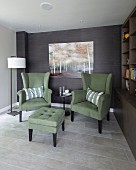 Green armchairs and footstool next to bookcase in comfortable seating area