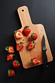 Halved strawberries on a wooden chopping board