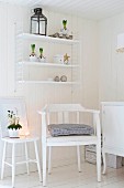 Weiß lackierter Armlehnstuhl und romantisch dekorierter Hocker vor Holzwand mit aufgehängtem String Regal in ländlichem Ambiente
