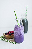 A blueberry smoothie in a bottle with a straw