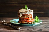 A stack of fried aubergines, tomatoes and mozzarella garnished with fresh basil