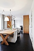 Pale grey upholstered chairs and classic shell chair around long solid-wood dining table in modern interior