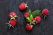 Raspberries with leaves on wooden surface