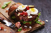 Beef tatar burger with egg, onions, ketchup and gherkins
