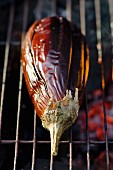 A whole aubergine on a barbecue