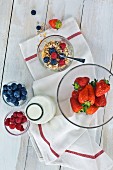 Gesundes Frühstück: Müsli mit frischen Früchten und Milch, Erdbeeren, Himbeeren, Heidelbeeren auf Holztisch