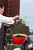 A cook serving mussels at a wedding by the sea