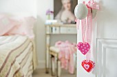 Offene Tür zum romantischen Schlafraum mit pinkfarbenen Herzchen an Schleifenbändern