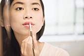 Woman applying lipstick with a brush