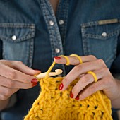 A woman holding a piece of yellow crochet work
