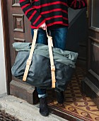 A woman carrying a large holdall coming out of a door