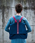 A woman carrying a canvas rucksack on her back