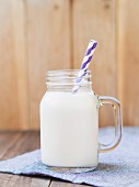Homemade organic almond milk in a glass with a paper straw