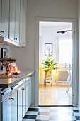 View of small Christmas tree in dining room from kitchen with chequered floor