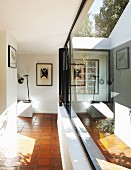 Reflections in glass façade of foyer with terracotta floor in modern bungalow