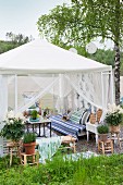 Romantisch möblierter Gartenpavillon mit luftig drapierten Vorhängen und Topfpflanzen