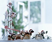 Festive arrangement of dog ornaments wearing Father Christmas hats and colourful ribbons amongst artificial snow