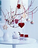 Zweige in Vase weihnachtlich dekoriert mit Baumkugeln und selbstgebastelten Filzanhängern in Rot und Weiß