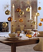 Gold baubles, white candles and sparkling stars hung above set dining table