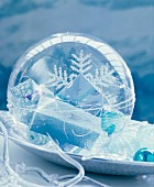 Plexiglas bauble filled with small wrapped gifts on decorative plate