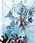Fairy-tale Christmas arrangement of glass baubles, twigs and fish decorations in glass vase