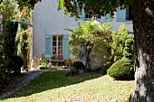 Sunny garden of country house with pale blue shutters