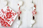 Weihnachtliche Wanddekoration mit Servietten, Dekokugeln, Zapfen & Herzen