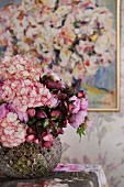 Romantic bouquet in glass vase on table in front of painting on wall