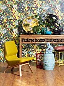 Yellow designer armchair and Chinese ornaments on console table against patterned wallpaper