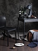 Gothic atmosphere with stylised knight's-helmet lamp, wine, chair and jumble of objects on charcoal-grey table